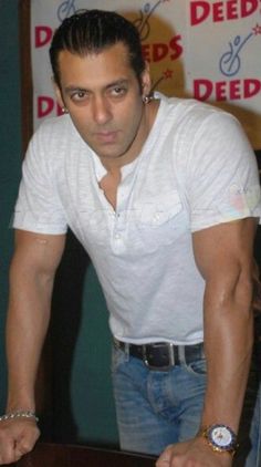 a man in white shirt leaning over a table with his hand on the top of it