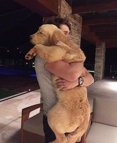 a man holding a large brown dog in his arms