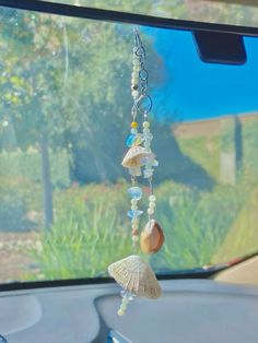 a car dashboard with shells and beads hanging from it's side window, in front of the sunroof