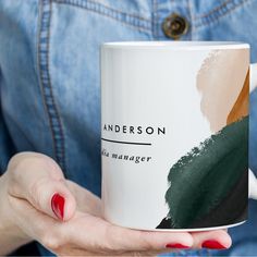 a woman holding a coffee mug with the name anderson on it in front of her