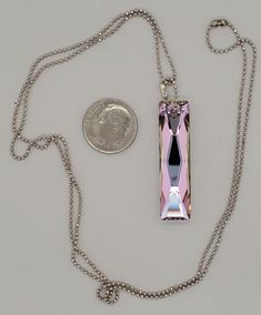 Pink Swarovski Bar Pendant has a long feceted rectangle crystal with silver back. Sparkle is mainly pink and golden. Chain is faceted ball chain in silver finish. Closure is a matching ball chain connector. The 25-inch-long chain can be shortened upon request. Designed and created by Tara of Takeen Arts. Item N192. Silver Faceted Rectangular Jewelry, Bar Pendant Necklace, Pink Swarovski, Rose A, Golden Chain, Bar Pendant, Long Chain, Ball Chain, Jewelry Necklace Pendant