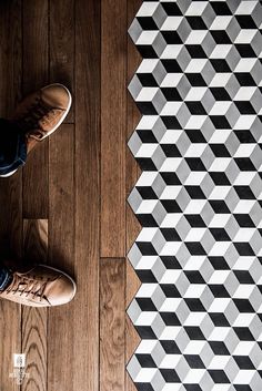 a person standing on top of a wooden floor next to a black and white pattern