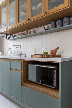 a kitchen with wooden cabinets and white tile backsplash, gray countertops and light green cupboards