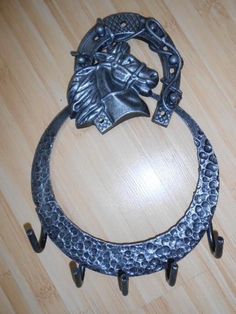 a metal horse head hanging from a hook on a wooden floor with two hooks attached to it