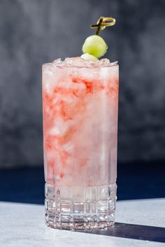 a tall glass filled with ice and a green apple sitting on top of a table