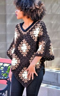 a woman standing next to a bench wearing a crocheted ponchy with flowers on it