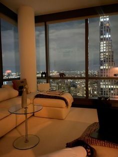 a living room filled with furniture next to a large window covered in night time lights