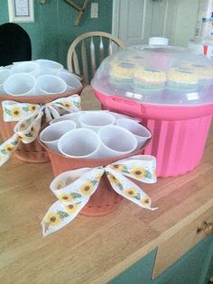 cupcakes in flower pots with ribbons on the counter top next to an icebox