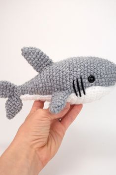 a hand holding a gray knitted shark toy