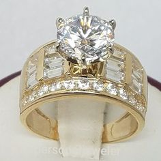 a gold ring with two rows of diamonds on the side and a center stone in the middle