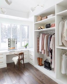 a white closet filled with lots of clothes next to a desk and window sill