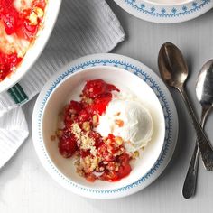 two bowls filled with ice cream and strawberries on top of a white tablecloth