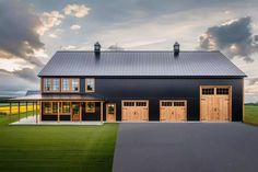 a large black barn with two garages and three windows on the side of it