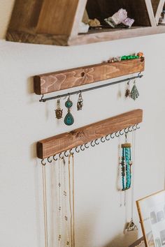 a wooden shelf with jewelry hanging from it's sides next to a framed photograph