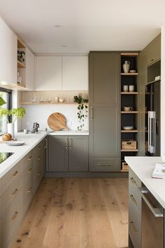 a large kitchen with wooden floors and gray cabinetry, white counter tops and wood flooring