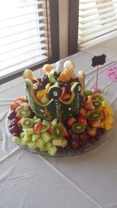 a platter filled with lots of fruit on top of a white cloth covered table