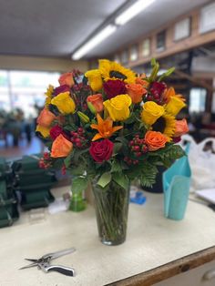 a vase filled with lots of colorful flowers on top of a table next to scissors