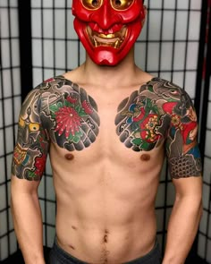 a man wearing a red mask with tattoos on his chest