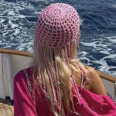 a woman sitting on the back of a boat looking at the ocean with long blonde hair