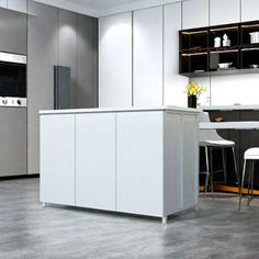 a modern kitchen with stainless steel appliances and white countertops, along with bar stools