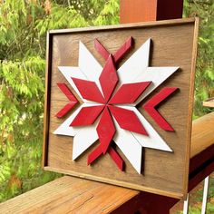 a red and white paper snowflake sitting on top of a wooden frame