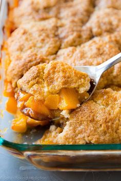 a close up of a spoon in a casserole dish with peach cobbler