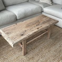 a wooden table sitting on top of a carpeted floor next to a white couch