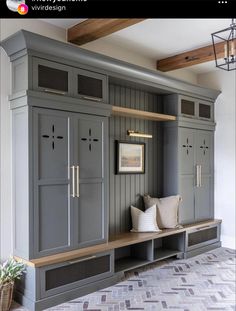 a room that has some gray cabinets and pillows on the bench in front of it