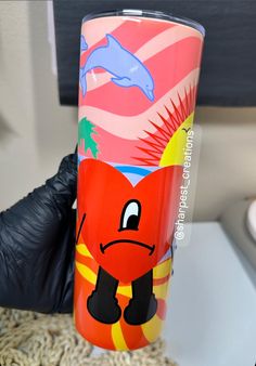 a hand holding a colorful tumbler cup with an image of a cartoon character on it