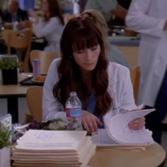 a woman is sitting at a table with books