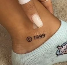 a woman's foot with a small tattoo on her left ankle and the word 999 written in black ink