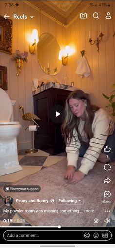 a woman kneeling down on the floor in front of a toilet and looking at her phone screen