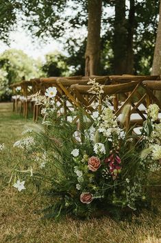 an arrangement of flowers on the ground in front of rows of wooden chairs at a wedding ceremony