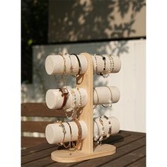 a wooden rack with rings and bracelets hanging from it's sides on a table