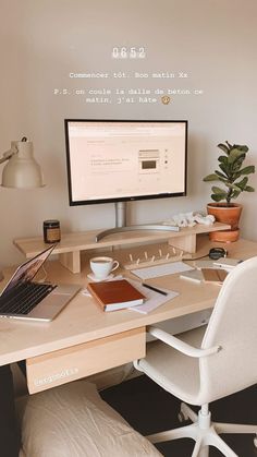 a computer desk with a laptop, monitor and keyboard on it in front of a white wall