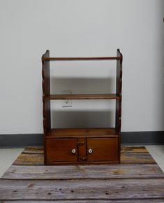 a wooden shelf with two drawers on top of it and a rug in front of it