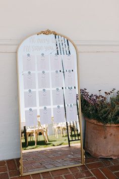 a large mirror sitting on top of a brick floor next to a potted plant