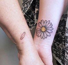 two people holding hands with tattoos on their arms and one has a flower on the wrist