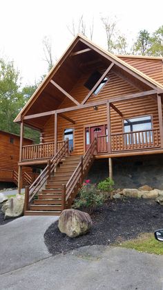 a wooden cabin with stairs leading up to the front door and second story deck area