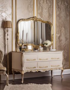 an ornate dresser with a mirror and vase on it in front of a wallpapered wall