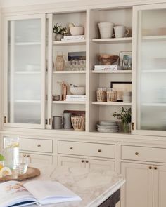 a kitchen with white cabinets and marble counter tops in front of the glass doored cabinet doors