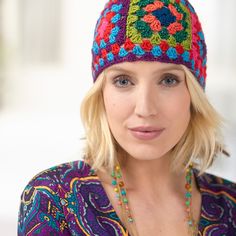 a woman with blonde hair wearing a multicolored crocheted beanie hat