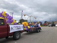 a parade float with balloons and decorations in the bed of a red pick - up truck