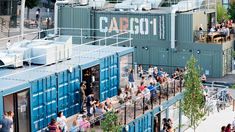 many people are standing on the balcony of a shipping container