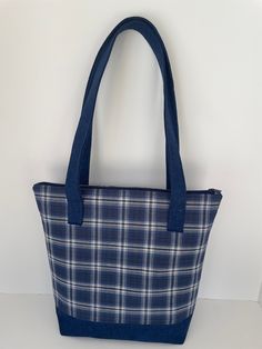 "Lightweight, stylish, and sized to carry your essentials and more!  This fully-lined shoulder tote bag is a dark blue plaid, with sewn-in straps and band around the base in a matching solid blue.  Inside are six large slip pockets in a coordinating blue print that help keep you organized.   The bag has a reinforced base that allows it to stand on its own.  Extra length straps with an 11\" drop.  Secure top zipper closure.    Dimensions:  12\" high, 10.5\" wide at base, 13\" wide at top, 4\" deep at base. Made of 100% cotton fabrics.      Washable; easy care.  Made in a pet and smoke free environment." Dark Blue Plaid, Zippered Tote, Top 4, Cotton Fabrics, Shoulder Tote Bag, Shoulder Tote, Blue Print, Blue Plaid, Purses And Handbags