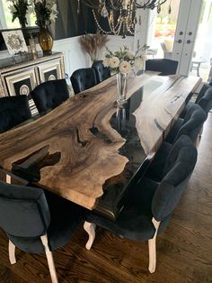 a dining room table with black chairs and a chandelier hanging from the ceiling