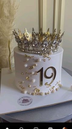 a white cake with gold decorations and a crown on top that reads'19 '