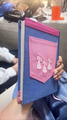 a person holding up a blue and pink book