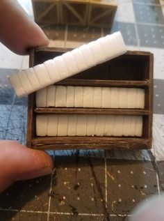 a person is holding two pieces of white paper in a wooden box on a table