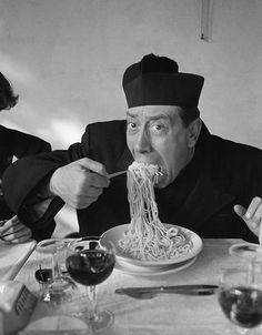 a man in a turban eating noodles with chopsticks at a table